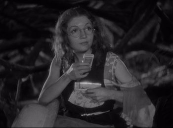 Movie still from “Four Frightened People” (1934), directed by Cecil B. DeMille – A woman sitting on a chair holding a drink; Medium shot, Low angle