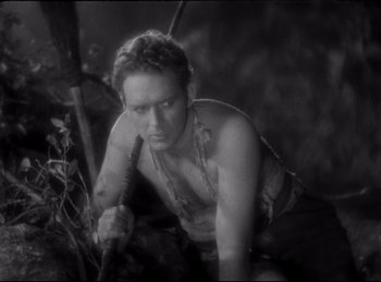 Movie still from “Four Frightened People” (1934), directed by Cecil B. DeMille – A man holding an arrow in a forest; Medium shot, High angle