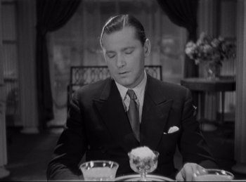 Movie still from “Four Frightened People” (1934), directed by Cecil B. DeMille – A black and white photo of a man sitting at a dinner table; Medium shot, High angle