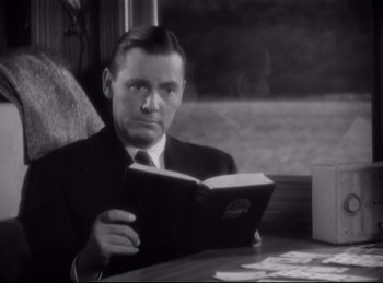 Movie still from “Four Frightened People” (1934), directed by Cecil B. DeMille – A black and white photo of a man reading a book; Close Up shot, High angle