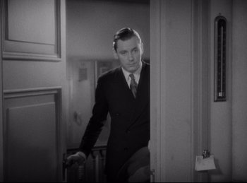 Movie still from “Four Frightened People” (1934), directed by Cecil B. DeMille – A black and white photo of a man in a suit and tie; Medium shot, Over the shoulder angle