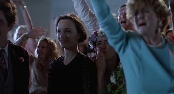 Movie still from “Four Weddings and a Funeral” (1994), directed by Mike Newell – A group of people standing in a room with arms raised; Medium shot, Over the shoulder angle