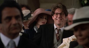 Movie still from “Four Weddings and a Funeral” (1994), directed by Mike Newell – A man and a woman wearing hats and suits; Close Up shot, Over the shoulder angle