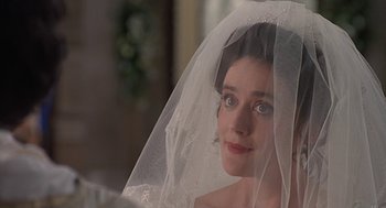 Movie still from “Four Weddings and a Funeral” (1994), directed by Mike Newell – A woman wearing a wedding veil looking at the camera; Close Up shot, Over the shoulder angle