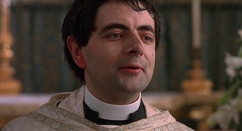 Movie still from “Four Weddings and a Funeral” (1994), directed by Mike Newell – A person wearing a priest's outfit; Close Up shot, Low angle