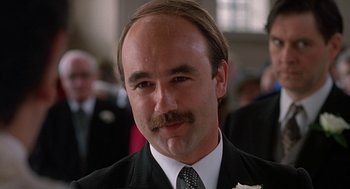 Movie still from “Four Weddings and a Funeral” (1994), directed by Mike Newell – A person wearing a suit and tie; Close Up shot, Low angle