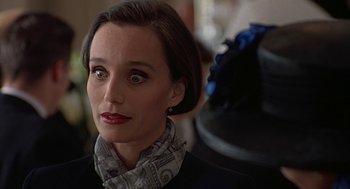 Movie still from “Four Weddings and a Funeral” (1994), directed by Mike Newell – A person wearing a suit and a scarf; Close Up shot, Over the shoulder angle