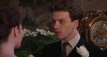 A man in a suit and tie standing in front of flowers