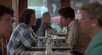Movie still from “Four Weddings and a Funeral” (1994), directed by Mike Newell – A man and a woman sitting at a table in a restaurant; Medium shot, Over the shoulder angle