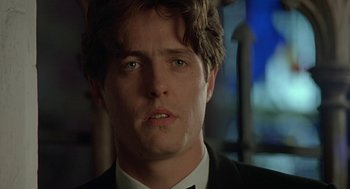 Movie still from “Four Weddings and a Funeral” (1994), directed by Mike Newell – A person wearing a suit and tie; Close Up shot, Low angle