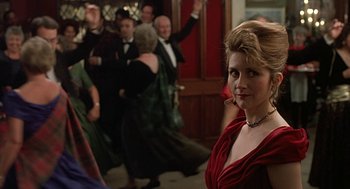 Movie still from “Four Weddings and a Funeral” (1994), directed by Mike Newell – A woman in a red dress is posing for a picture; Medium shot, Over the shoulder angle