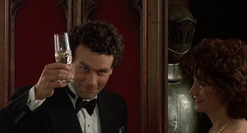 Movie still from “Four Weddings and a Funeral” (1994), directed by Mike Newell – A man in a tuxedo holding a glass of wine; Close Up shot, Low angle