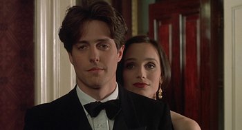 Movie still from “Four Weddings and a Funeral” (1994), directed by Mike Newell – A man and a woman in formal wear standing next to each other; Close Up shot, Over the shoulder angle