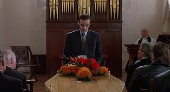 A man in a suit standing at a table with flowers