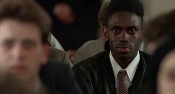 Movie still from “Four Weddings and a Funeral” (1994), directed by Mike Newell – A man wearing a suit and tie sitting in front of another man wearing a suit and tie; Close Up shot, High angle