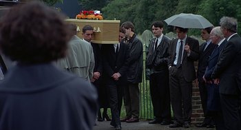 Movie still from “Four Weddings and a Funeral” (1994), directed by Mike Newell – A group of men standing around a casket; Wide shot, Low angle