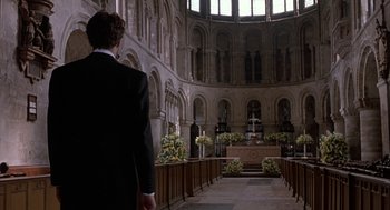 Movie still from “Four Weddings and a Funeral” (1994), directed by Mike Newell – A man in a suit standing in front of an altar; Extreme Wide shot, Low angle