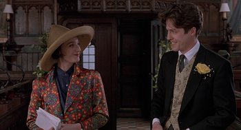Movie still from “Four Weddings and a Funeral” (1994), directed by Mike Newell – A man and a woman standing next to each other in a room; Medium shot, Over the shoulder angle