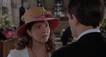 Movie still from “Four Weddings and a Funeral” (1994), directed by Mike Newell – A woman wearing a pink hat talking to a man in a black suit; Close Up shot, Over the shoulder angle