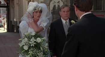 Movie still from “Four Weddings and a Funeral” (1994), directed by Mike Newell – A woman in a wedding dress standing in front of two men; Medium shot, Over the shoulder angle
