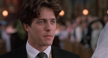 Movie still from “Four Weddings and a Funeral” (1994), directed by Mike Newell – A person wearing a suit and tie; Close Up shot, Low angle