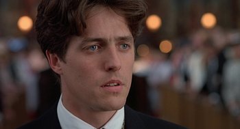 Movie still from “Four Weddings and a Funeral” (1994), directed by Mike Newell – A person wearing a suit and tie; Close Up shot, Low angle