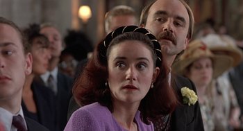 Movie still from “Four Weddings and a Funeral” (1994), directed by Mike Newell – A man and a woman standing next to each other in front of a crowd; Close Up shot, Over the shoulder angle