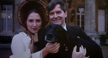 Movie still from “Four Weddings and a Funeral” (1994), directed by Mike Newell – A man and a woman holding a black dog; Close Up shot, Low angle