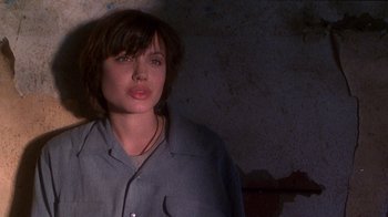 Movie still from “Foxfire” (1996), directed by Annette Haywood-Carter – A woman in a blue shirt is standing in a room; Close Up shot, Low angle