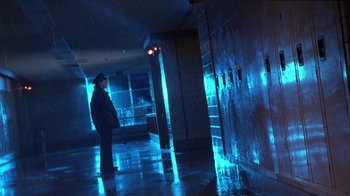 Movie still from “Foxfire” (1996), directed by Annette Haywood-Carter – A man standing in a hallway next to a red light; Wide shot, Low angle