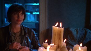 Movie still from “Foxfire” (1996), directed by Annette Haywood-Carter – A woman sitting in front of a table with lit candles; Medium shot, Over the shoulder angle