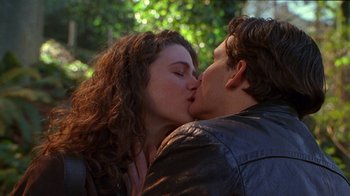 Movie still from “Foxfire” (1996), directed by Annette Haywood-Carter – A man and a woman kissing each other in a park; Close Up shot, Low angle