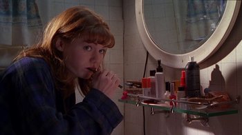 Movie still from “Foxfire” (1996), directed by Annette Haywood-Carter – A woman brushing her teeth in a bathroom; Medium shot, Low angle