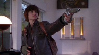 Movie still from “Foxfire” (1996), directed by Annette Haywood-Carter – A person holding a gun in a room; Medium shot, Low angle