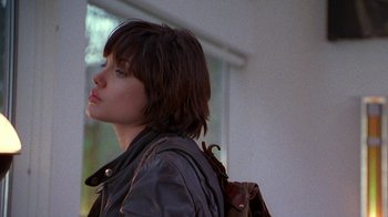 Movie still from “Foxfire” (1996), directed by Annette Haywood-Carter – A young woman with a brown backpack looking to the side; Close Up shot, Over the shoulder angle
