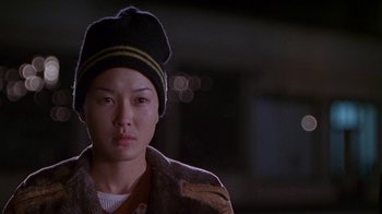 Movie still from “Foxfire” (1996), directed by Annette Haywood-Carter – A woman wearing a black hat and a brown coat; Close Up shot, Over the shoulder angle