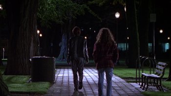 Movie still from “Foxfire” (1996), directed by Annette Haywood-Carter – Two people are walking on a sidewalk at night; Wide shot, Over the shoulder angle