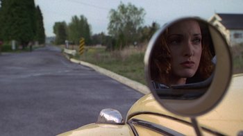 Movie still from “Foxfire” (1996), directed by Annette Haywood-Carter – A woman is reflected in a mirror of a car; Close Up shot, Over the shoulder angle