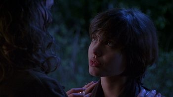 Movie still from “Foxfire” (1996), directed by Annette Haywood-Carter – A young woman looking at the camera while a man touches her face; Close Up shot, Over the shoulder angle