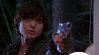 Movie still from “Foxfire” (1996), directed by Annette Haywood-Carter – A woman is holding a gun in her hand; Close Up shot, Over the shoulder angle