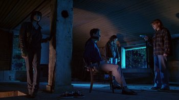Movie still from “Foxfire” (1996), directed by Annette Haywood-Carter – A man and a woman sitting on a chair in the dark; Wide shot, Low angle