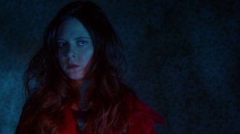 Movie still from “Foxfire” (1996), directed by Annette Haywood-Carter – A woman in a red coat is standing in the dark; Close Up shot, High angle