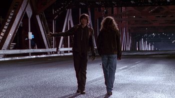 Movie still from “Foxfire” (1996), directed by Annette Haywood-Carter – Two people are walking on the street at night; Wide shot, Over the shoulder angle