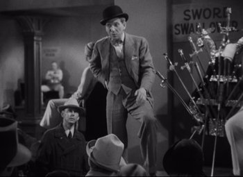 Movie still from “Freaks” (1932), directed by Tod Browning – An old photo of a man in a suit and a hat; Medium shot, High angle