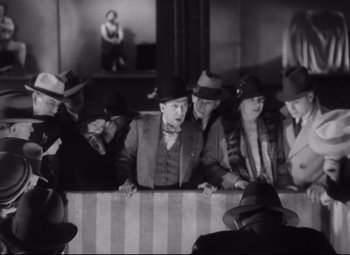 Movie still from “Freaks” (1932), directed by Tod Browning – A black and white photo of a group of people in hats; Medium shot, High angle