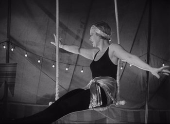 Movie still from “Freaks” (1932), directed by Tod Browning – A woman is sitting on a swing in a circus; Wide shot, Low angle
