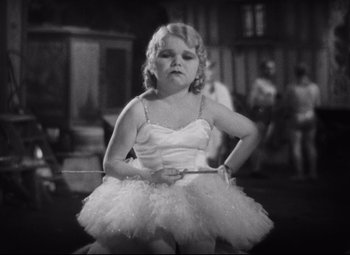 Movie still from “Freaks” (1932), directed by Tod Browning – A little girl in a white dress holding onto a rope; Medium shot, High angle