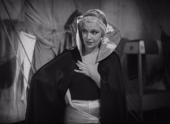Movie still from “Freaks” (1932), directed by Tod Browning – A black and white photo of a woman wearing a cape; Medium shot, Low angle