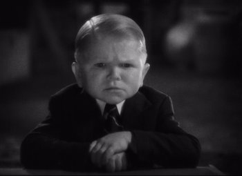 Movie still from “Freaks” (1932), directed by Tod Browning – A little boy wearing a suit and tie; Close Up shot, High angle
