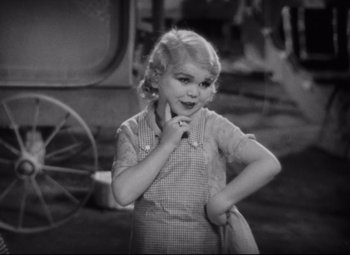 Movie still from “Freaks” (1932), directed by Tod Browning – A little girl standing in front of an old fashioned carriage; Close Up shot, High angle